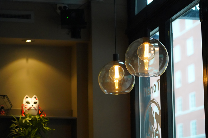 Fokus på lampor i lokalen hos Tonari Ramen i Stockholm.